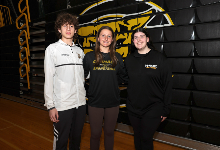 The three student-athletes pose for a photo in the gym.