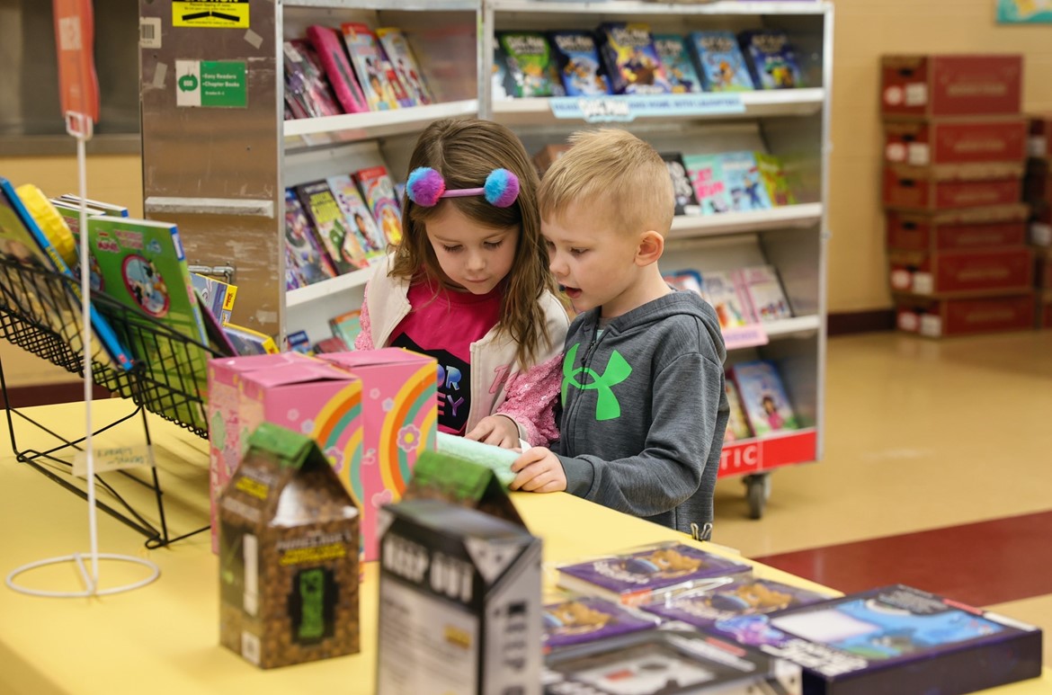 Pair of kindergarteners look at a book during the book fair.