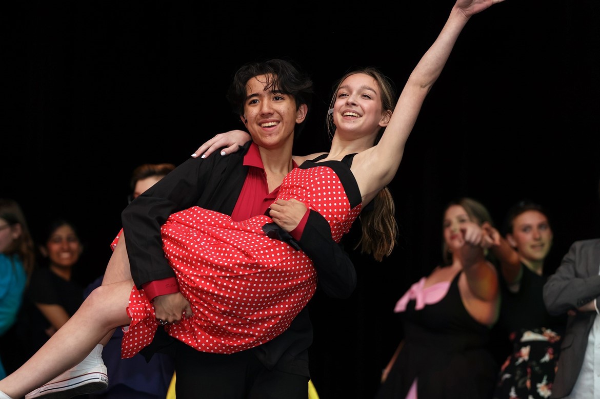 Two lead characters in CHS production of Grease perform, with male character holding female character.